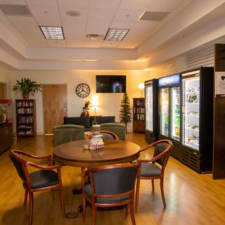 A cozy lounge area with a round table and chairs, surrounded by refrigerators and a television.