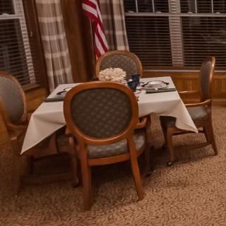 A cozy dining setup with four chairs and an elegantly set table, accompanied by a flag in the background.