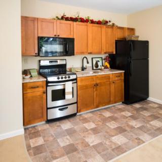 A modern kitchen with wooden cabinets, a stove, microwave, and refrigerator.