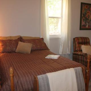 A cozy bedroom with a bed, chair, and window.