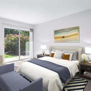 A modern bedroom with a large bed, stylish furniture, and natural light streaming through a sliding glass door.