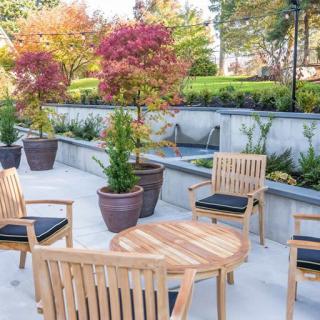 A beautifully arranged outdoor patio with wooden furniture and potted plants in an autumn setting.