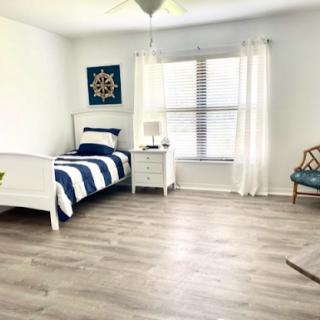 A bright and modern bedroom featuring a blue and white color scheme, natural light filtering through the windows, and minimalist decor.
