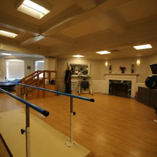 A spacious dance studio featuring a barre for exercise and rehabilitation.