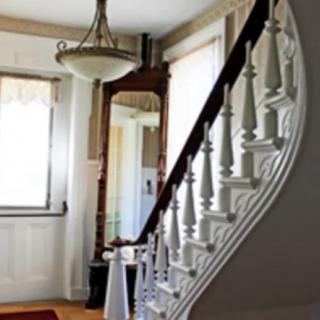 A well-lit hallway with a spiral staircase and chandelier.