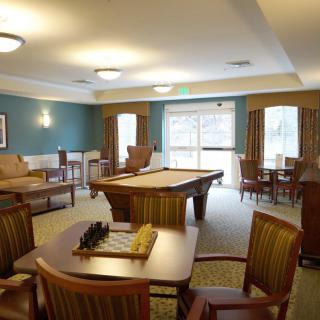 A cozy recreation room with a pool table, chess board, and ample seating.