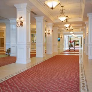 A luxurious hallway with chandeliers and red carpeting.