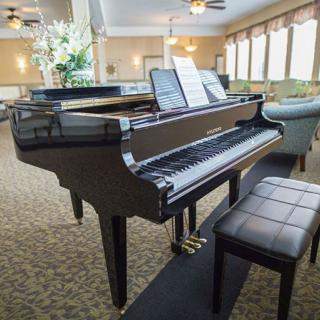 A grand piano with sheet music in a well-lit music room.