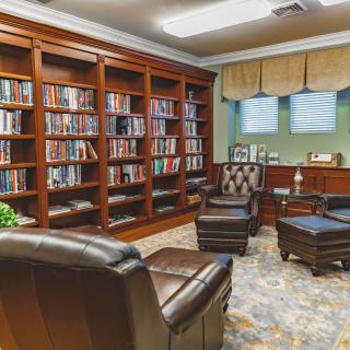 A cozy library with wooden bookshelves filled with books, comfortable leather armchairs, and a warm atmosphere.