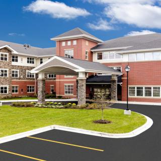 A modern residential building with a landscaped lawn and driveway.