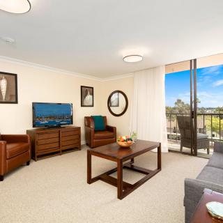 A modern living room with comfortable seating, a television, and a view from the balcony.