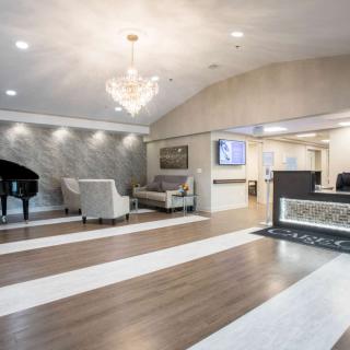 A modern lobby with elegant furnishings, featuring a grand piano and chandelier.