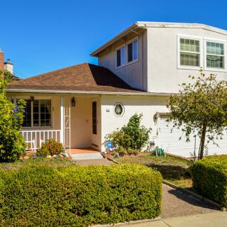 A suburban house with well-maintained landscaping and a clear blue sky.