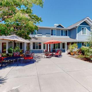 A spacious residential building with a welcoming patio area featuring outdoor seating and umbrellas on a sunny day.