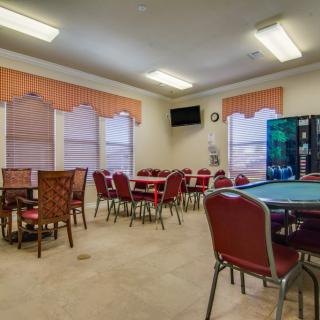 A spacious meeting room with multiple tables and chairs, featuring a vending machine and a wall-mounted television.