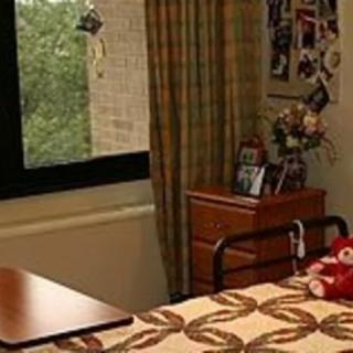 A cozy dorm room with a bed, window, and personal decorations.