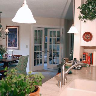 A cozy kitchen interior with a dining area, featuring plants and warm lighting.