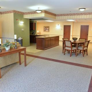 A comfortable and well-decorated living room with a dining table and chairs, carpeted flooring, and ambient lighting.