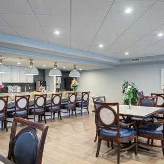 A modern dining area with tables and chairs, featuring a bar counter and contemporary lighting.