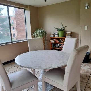 A cozy dining area with a round table and four chairs, adjacent to a large window with natural light.