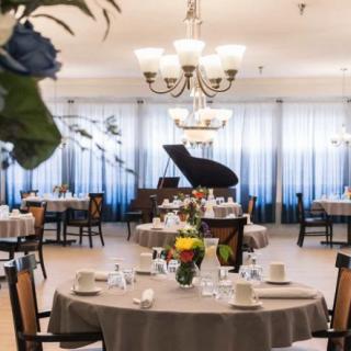 A formal dining area with elegantly set tables and a grand piano in the background.