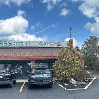 A view of a business with parked cars and a partly cloudy sky.
