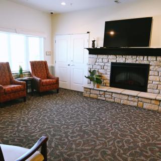 A cozy living room area featuring a stone fireplace, television, and comfortable armchairs.