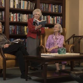 A group of seniors enjoying a book reading session in a cozy library setting.