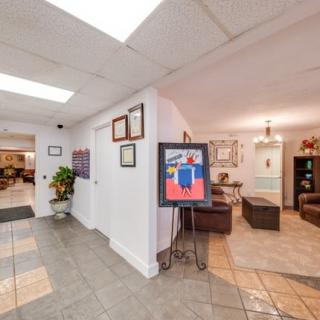 A well-lit lobby area featuring artwork on an easel, comfortable seating, and decorative elements.
