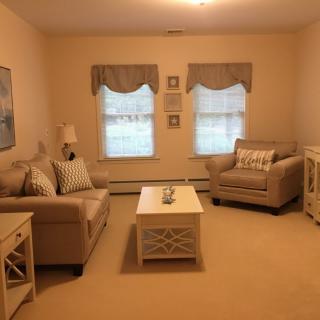 A cozy living room featuring a sofa, armchair, and coffee table, with warm lighting and simple decor.
