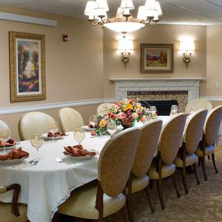 An elegantly set dining room with a long table, adorned with flowers and lit by chandeliers.