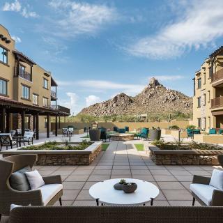 A scenic outdoor patio with seating, offering a stunning mountain view surrounded by buildings.