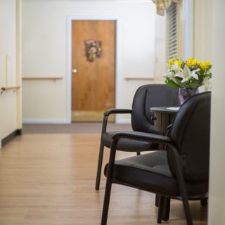 A quiet waiting area with chairs and a small table with flowers in a hallway.