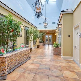 A welcoming indoor hallway with chandeliers, plants, and a tile floor.