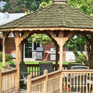 A wooden gazebo surrounded by greenery, offering a cozy outdoor space for relaxation.