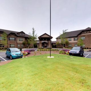 A view of a brick building with cars parked in front on a cloudy day.