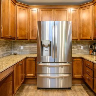 A modern kitchen featuring a stainless steel refrigerator surrounded by wooden cabinets.