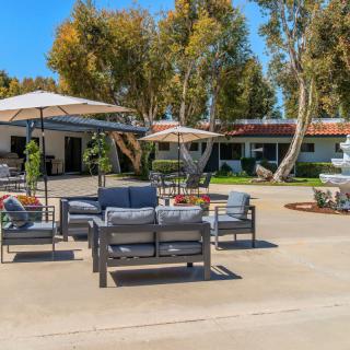 A sunny outdoor seating area with patio furniture and umbrellas, surrounded by trees.
