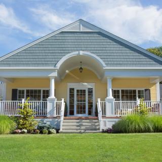 A charming single-story house with a welcoming porch and well-maintained front lawn.
