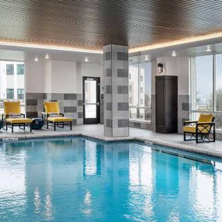 A modern indoor swimming pool with yellow chairs and large windows.