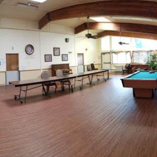 A spacious interior featuring a pool table and multiple tables for gatherings.