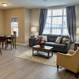 A cozy and well-decorated living room with a sofa, armchair, and dining area.