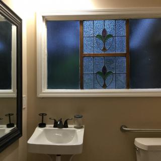 A bathroom with a stained glass window and a white sink.