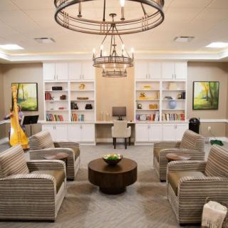 A modern living room with a central seating area, bookshelves, and a chandelier.