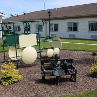 A vibrant playground area featuring unique equipment and a bench, surrounded by well-kept landscaping.