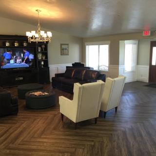 A cozy living room featuring a large TV, comfortable seating, and elegant wood flooring.