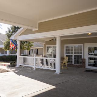 A welcoming porch of a residential building featuring flags and seating.