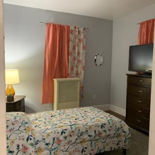 A cozy and inviting bedroom featuring colorful curtains, a patterned bedspread, and warm lighting.