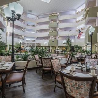 A spacious dining area with neatly arranged tables and chairs, accented by indoor plants and decorative lighting.