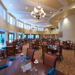 Elegant dining area with chandeliers and neatly arranged tables and chairs.